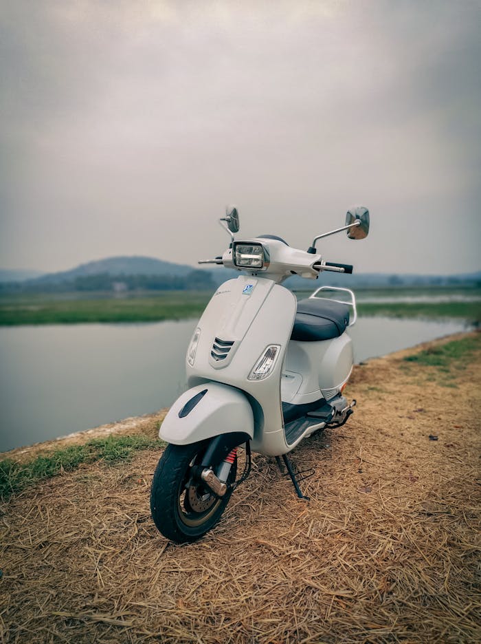 A stylish motor scooter by a serene riverside in Vijayawada, India, offering a rural travel vibe.