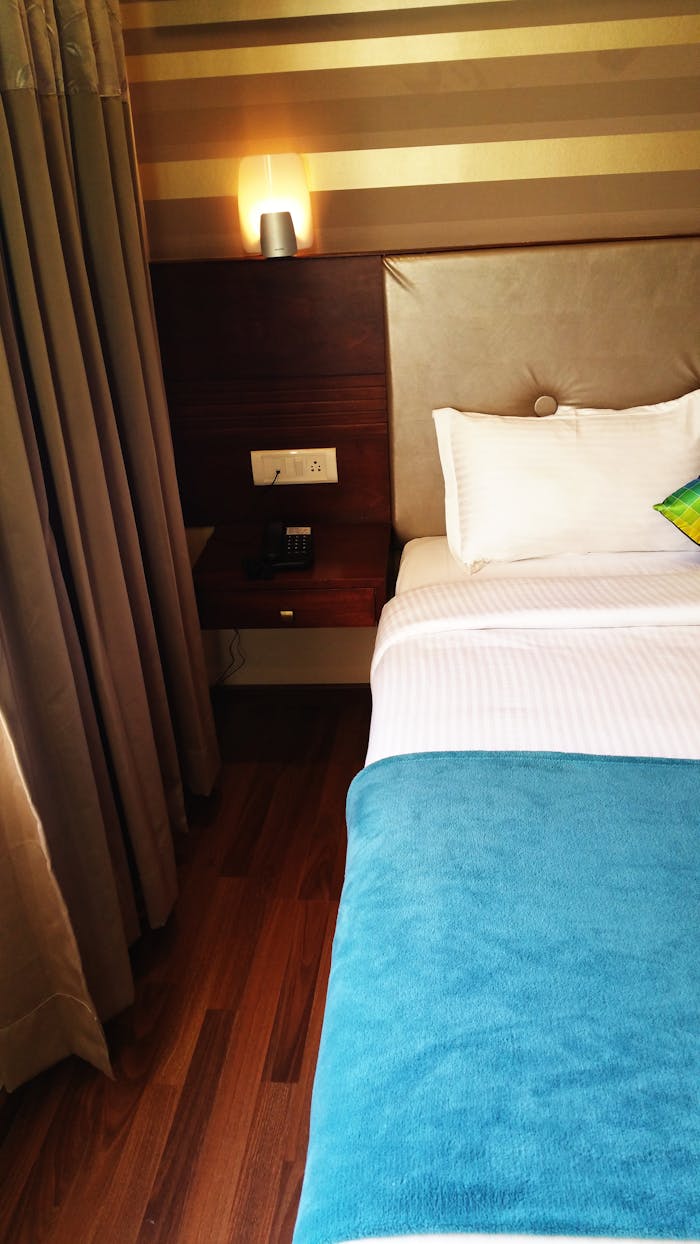 The Art of Drawing Readers In: Your attractive post title goes here A cozy and modern bedroom interior featuring a neatly made bed with a blue blanket and soft lighting.